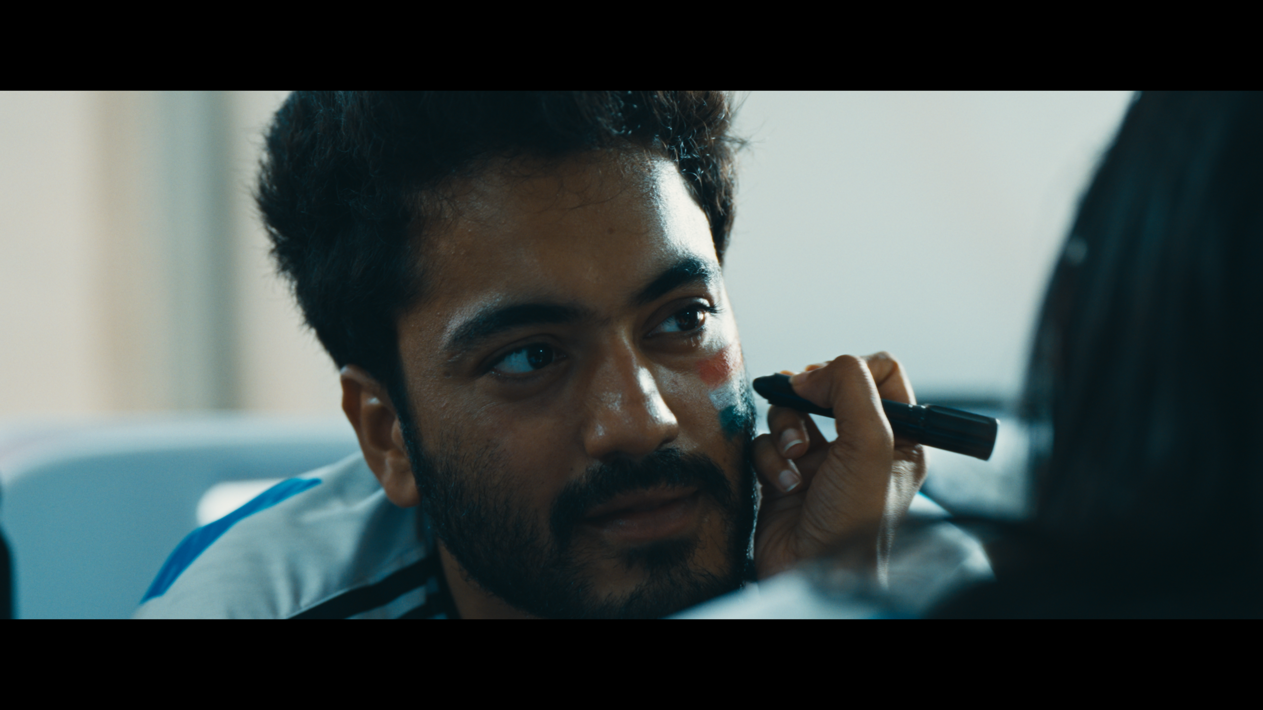 Yadav Shashidhar as Ashish getting a flag painted on his face from a still of 52 Blue film