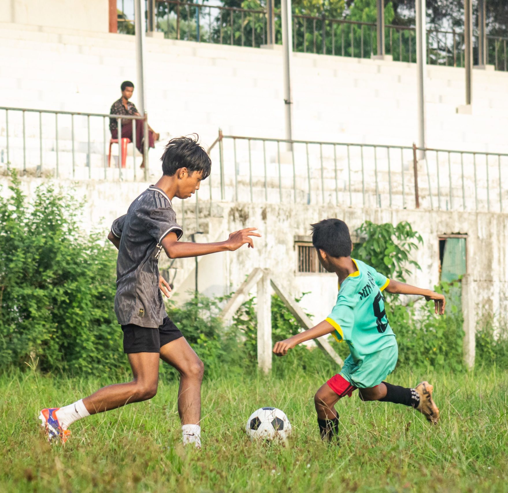 two boys playing football on a grassy patch 