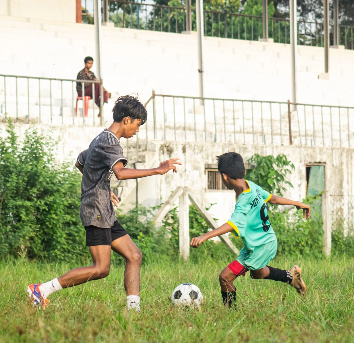 two boys playing football on a grassy patch two boys playing football on a grassy patch
