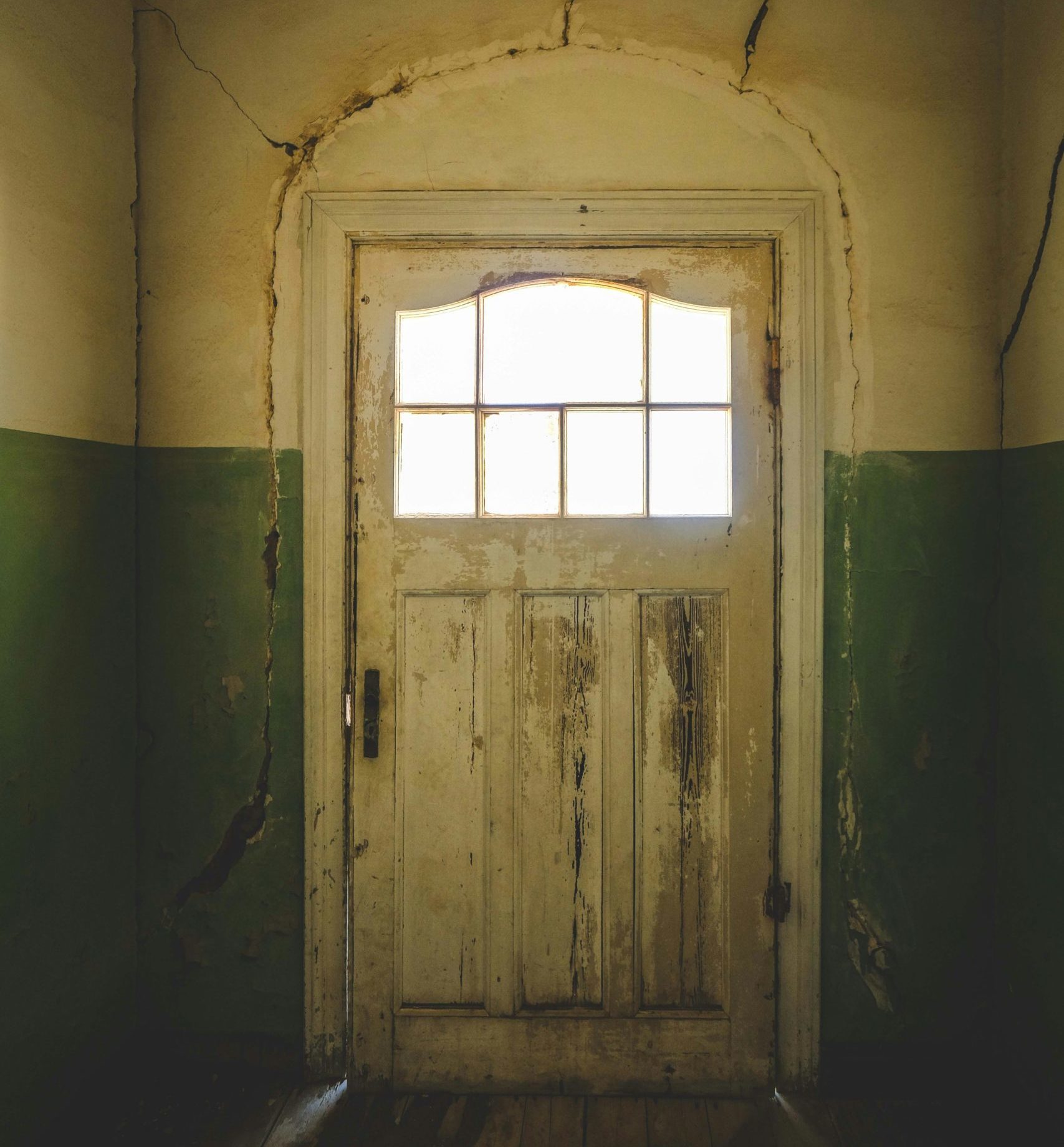 creepy white battered door viewed through a corridor like something out of a horror film.
