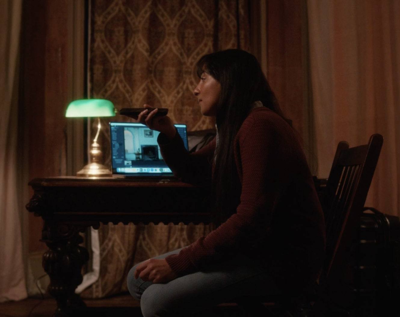 A Still from the movie Leave me Alone (2025) directed by Shehroze Khan. A South Asian woman sitting at a desk looking at images on her laptop with a phone in her hand.
